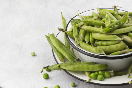 Green peas in metal bowls on a white backgroundの写真素材