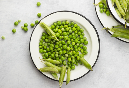 Green peas in metal bowls on a white backgroundの写真素材