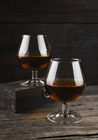 Cognac in two glasses on a dark wooden backgroundの写真素材