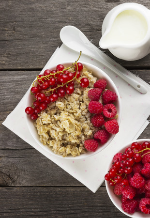 Oatmeal with raspberry and red currant on a wooden backgroundの写真素材