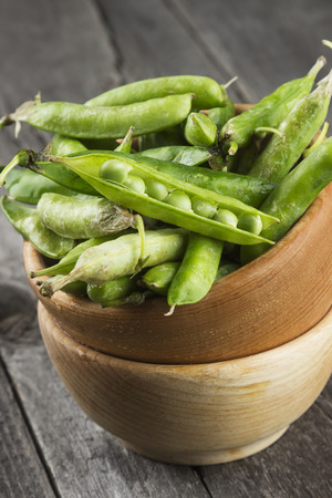 Green peas in wooden bowl on a white backgroundの写真素材