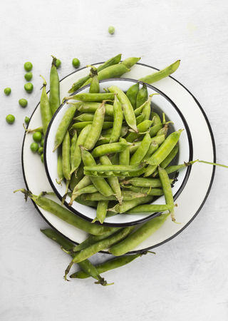 Green peas in metal bowls on a white backgroundの写真素材