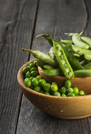 Green peas in wooden bowl on a white backgroundの写真素材