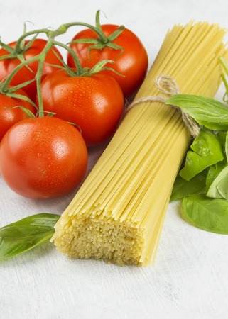 Ingredients for paste: spaghetti, basil and tomatoes on a white background.の写真素材