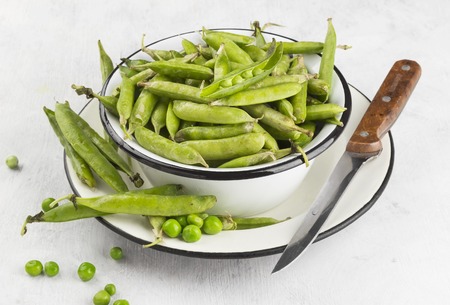 Green peas in metal bowls on a white background.の写真素材