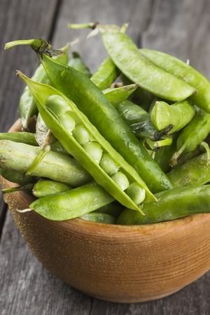 Green peas in wooden bowl on a white background.の写真素材