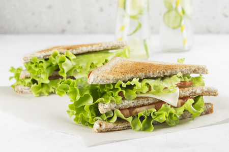 Sandwich with lettuce, cheese, tomato and lemonade on a white background.の写真素材