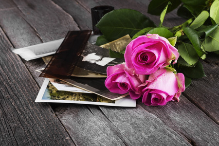 Old photos pink roses and chocolate on a dark wooden background.の写真素材