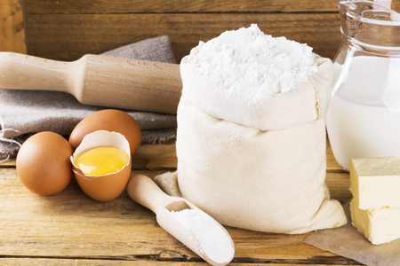 Ingredients for pastries - flour, eggs, butter, milk on a wooden backgroundの写真素材