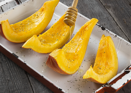 The pumpkin baked by slices with salt, herbs and honey on a dark backgroundの写真素材