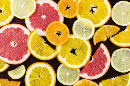 Various citrus: orange, lemon, tangerine, grapefruit on a dark background. Top view. Food background. Toning.の写真素材
