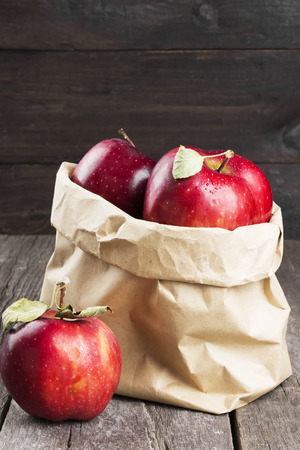 Harvest of apples in a paper package on a dark wooden background.の写真素材