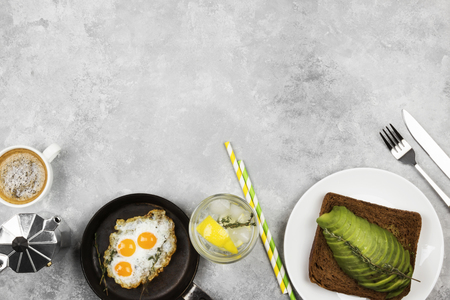 Traditional breakfast - toast from rye bread with avocado, fried eggs from quail eggs,  lemonade on a light background. Top view, copy space. Food backgroundの写真素材
