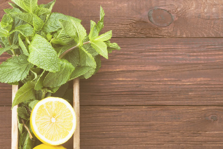 Ingredients for lemonade - lemon, mint in wooden box on a wooden background. Top view, copy space. Food background. Toningの写真素材