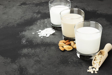 Vegan oat, almond, coconut milk in glass on a dark background. Non-dairy milk. Copy space. Food backgroundの写真素材