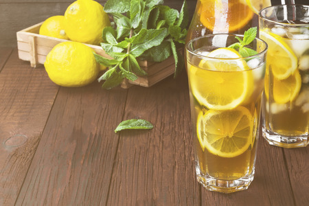 Ice tea with lemon and mint on a wooden background. Copy space. Food background. Toningの写真素材
