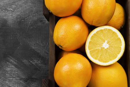 Oranges in a wooden box on a black background. Top view, copy space. Food backgroundの写真素材