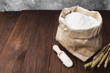 Paper package of wheat flour on a wooden background. Copy space. Food backgroundの写真素材