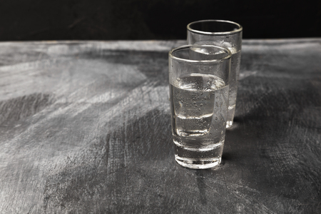 Cold vodka in shot glasses on a black background. Copy space. Food background