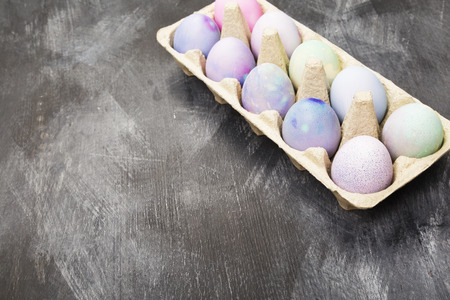 Multi-colored eggs for Easter in container for eggs on black background. Copy space