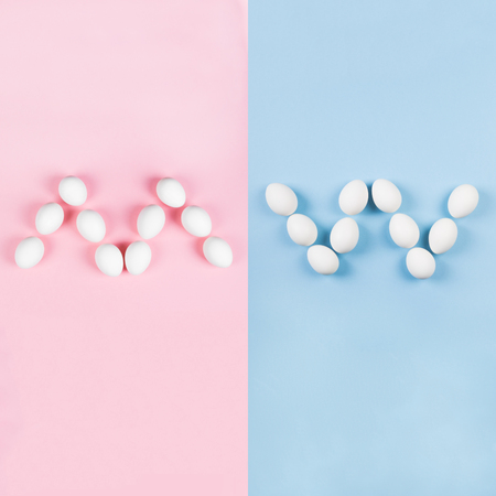 White eggs in form of letters "m" and "w" on blue and pink background. Concept gender stereotypes, role of man and woman in societyの写真素材