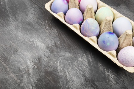 Multicolored eggs for Easter in container for eggs on black background. Copy spaceの写真素材
