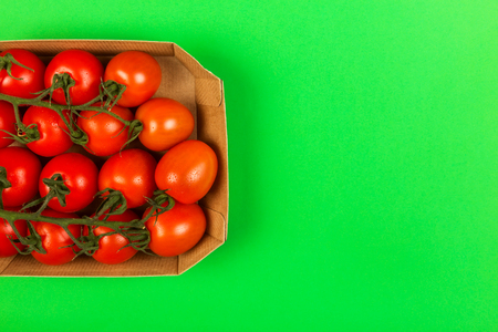 Red cherry tomatoes on green background. Top view, copy space. Food backgroundの写真素材