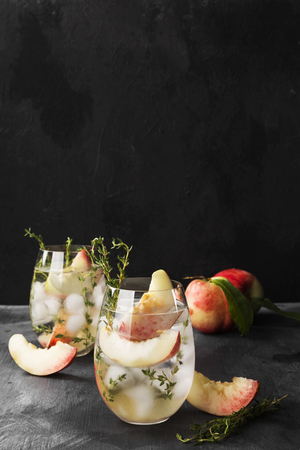 Peach nectarine cold lemonade with thyme different ingredients two glasses on dark background. Copy space. Food backgroundの写真素材