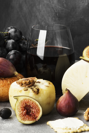 Snacks with wine - various types of cheeses, figs, nuts, honey, grapes on a gray backgroundの写真素材