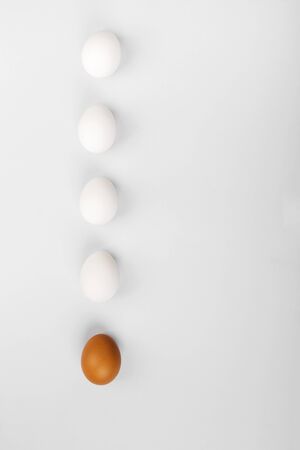Group of raw eggs white and brown. Concept of diversity, isolation, racism, inequality. On gray background. Top view, copy spaceの写真素材