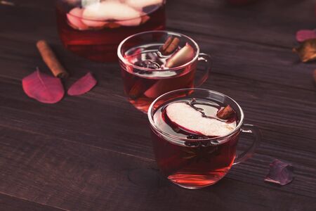 Hot drink with hibiscus red tea with apple, cinnamon and anise in glass teapot and two glasses on woodenの写真素材