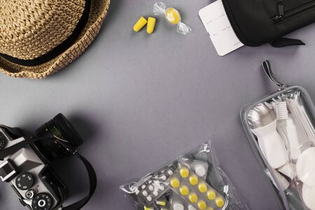 Set for flight small bottles with cosmetics, camera, hat, earplugs, medicine, air ticket and documents on grayの写真素材
