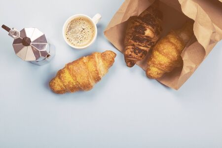 French breakfast - espresso and croissants in paper bag on blue background. Top view, copy spaceの写真素材