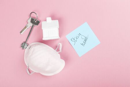 Concept of self-isolation and quarantine. Stay at home. White house, keys, mask and sticker with...
