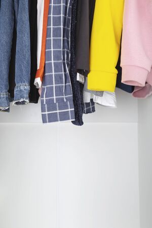 Various women's clothes hang in white closetの写真素材