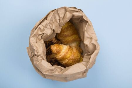 Breakfast to go - croissants on blue background. Delivery of products. Top view