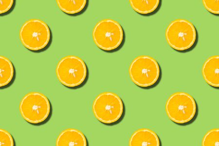 Colourful fruit seamless pattern of orange halves on green background. Top viewの写真素材