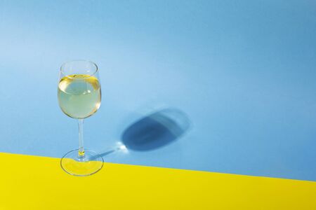 Glass of white wine on yellow and blueの写真素材