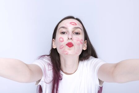 Funny young girl with traces of kisses on her face with red lipstickの写真素材