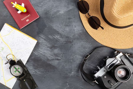 Tourist planning with map. Various accessories traveler on table, black background. Top view. Copy...