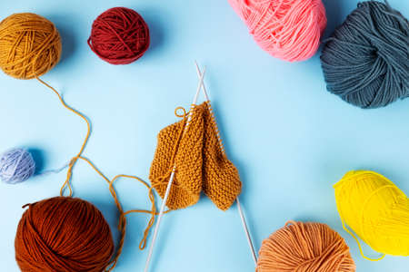 Color yarn for knitting, blue background. Knitting project in progress. Top view