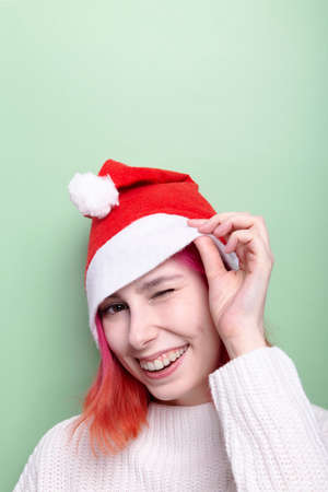 Woman in white sweater and wearing santa hat smiles, green backgroundの写真素材