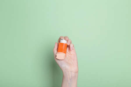 Hand holds inhaler to treat asthma. World Asthma Day. Concept of allergy careの写真素材