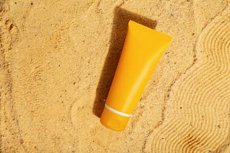 Orange tube of sunscreen on beach sand. Sun Protection. Top viewの写真素材