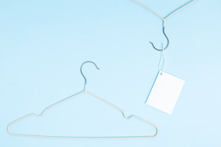 Creative flat lay hanger with white paper label blue background. Clothing tag, label blank mockup template. Sale discount store promo shopping concept. top view. copy spaceの写真素材