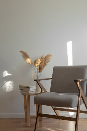 Wooden table with stack of books and vase with pampas grass, gray chair. Light minimalistic scandinavian interior.の写真素材