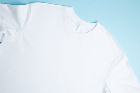 Basic folded white t-shirt blue background. Mock up for branding t-shirt. copy spaceの写真素材
