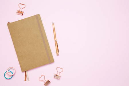 Creative flat lay mockup design of workspace. Top view composition with close notebook and stationery on pink backgroundの写真素材