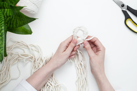 Creative hobby handmade macrame for home decoration. Girl weaves macrame. Woman weaving macrame panels for home decor. Flat lay, top viewの写真素材