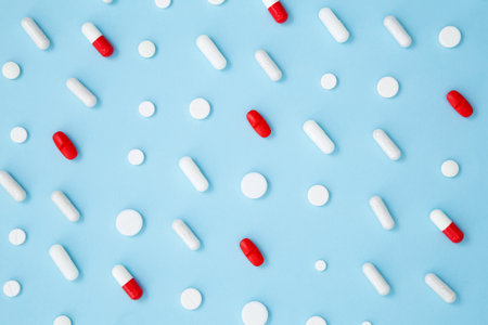 Various colorful medication tablets and capsules on blue background. Concept of healthcare and...